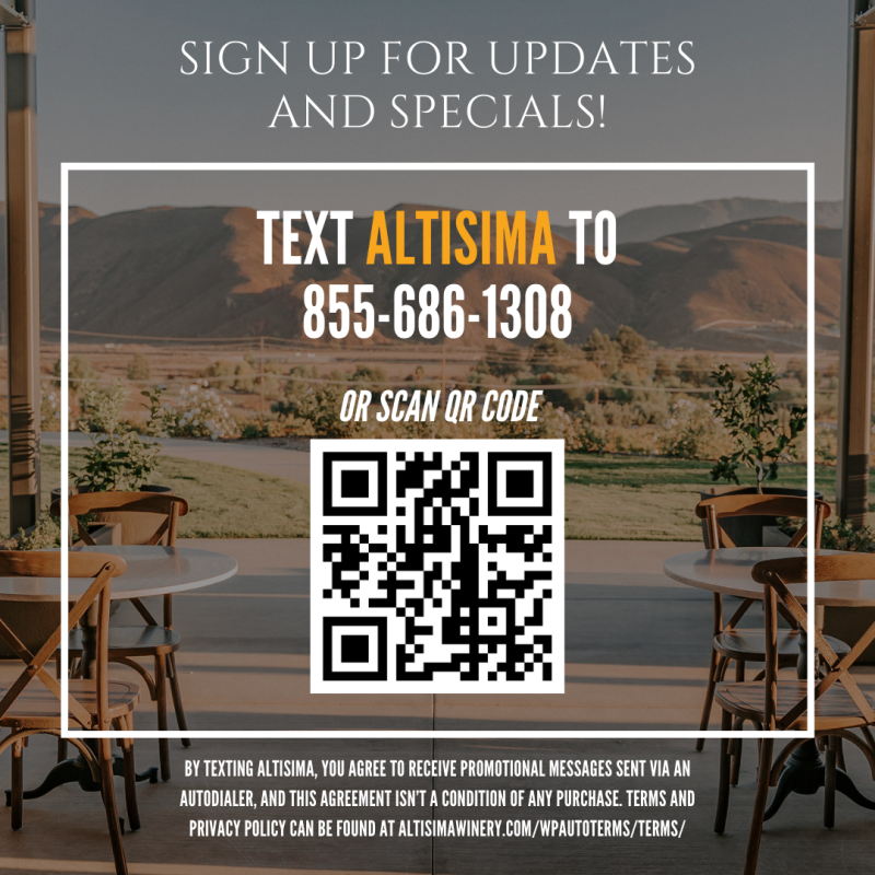 An outdoor patio table set overlooking a scenic view of hills and greenery. A sign encourages visitors to sign up for updates and specials by texting a number or scanning a QR code. Altisima Winery is mentioned.